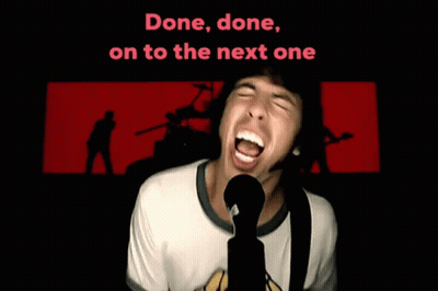 A Man Singing Into A Microphone With The Words " Done Done On To The Next One " Behind Him GIF