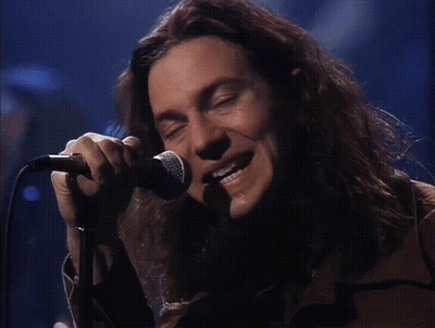 A Man Singing Into A Microphone With The Words He Looks Insane Behind Him GIF