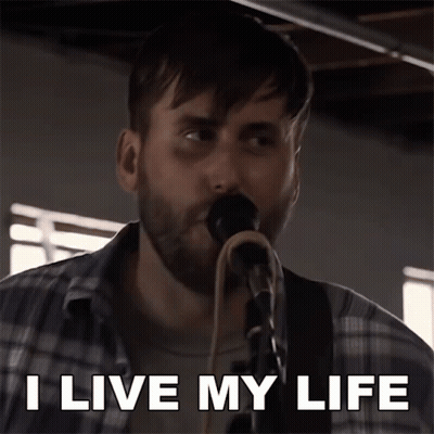 A Man Singing Into A Microphone With The Words I Live My Life Above Him GIF
