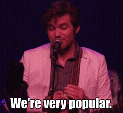 A Man Singing Into A Microphone With The Words " We 'Re Very Popular " Next To Him GIF