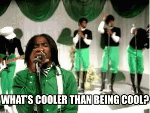 A Man Singing Into A Microphone With The Words " What 'S Cooler Than Being Cool " Above Him GIF