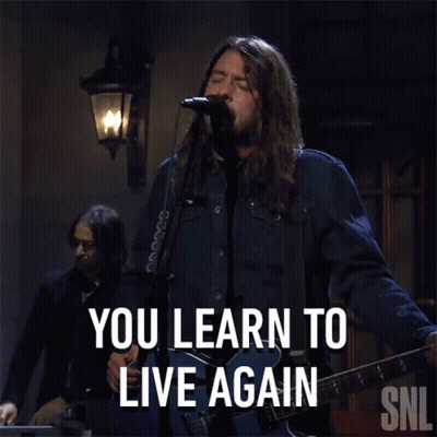 A Man Singing Into A Microphone With The Words You Learn To Live Again Behind Him GIF