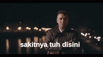 A Man Singing With The Words Sakitnya Tuh Disini Written Below Him GIF