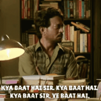A Man Sits At A Desk In Front Of A Bookshelf With The Words Kya Baat Hai Sir Written On The Bottom GIF