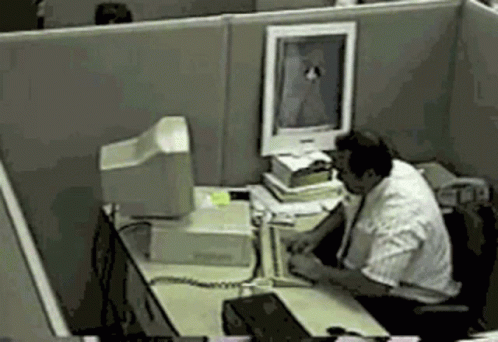 A Man Sits At A Desk In Front Of A Computer Screen GIF