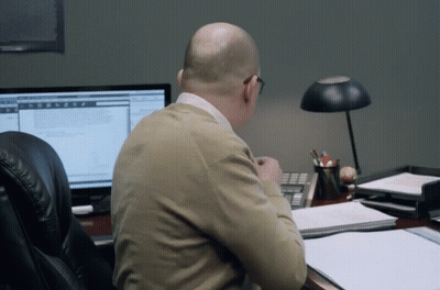 A Man Sits At A Desk In Front Of A Computer Screen GIF