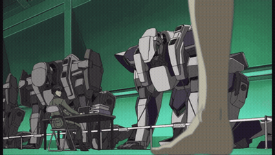 A Man Sits At A Desk In Front Of A Row Of Robots And A Person Standing Next To Them GIF