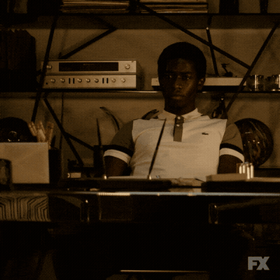 A Man Sits At A Desk In Front Of A Tv That Says Fx GIF