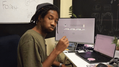 A Man Sits At A Desk In Front Of A White Board That Has The Word Forest Written On It GIF