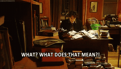A Man Sits At A Desk Surrounded By Books And Says " What Does That Mean " GIF