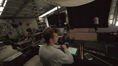 A Man Sits At A Desk With A Keyboard And A Phone In Front Of A Monitor That Says ' Korg ' On It GIF
