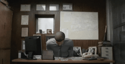 A Man Sits At A Desk With His Head Down In Front Of A Computer GIF