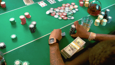 A Man Sits At A Poker Table With A Stack Of 100 Dollar Bills GIF