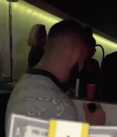 A Man Sits At A Table In A Dark Room With A Sign That Says ' Lg ' On It GIF