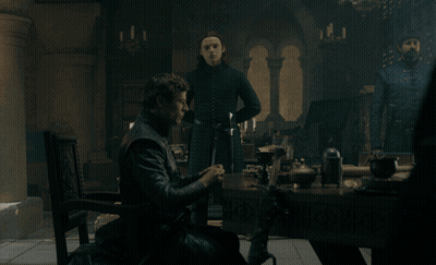 A Man Sits At A Table In A Dark Room With Candles GIF