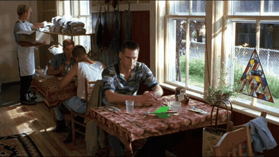 A Man Sits At A Table In Front Of A Stained Glass Window GIF