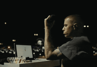 A Man Sits At A Table Using A Laptop And Drinking A Cup Of Coffee GIF