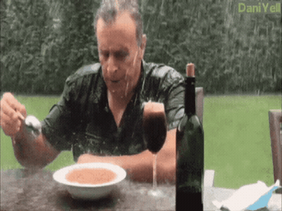 a man sits at a table with a bowl of soup and a glass of wine