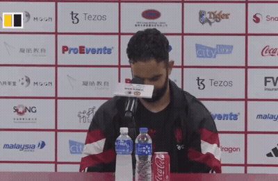 A Man Sits At A Table With A Can Of Coca-Cola And A Bottle Of Water GIF