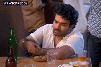 A Man Sits At A Table With A Sticker That Says 7Wickreddy On It GIF