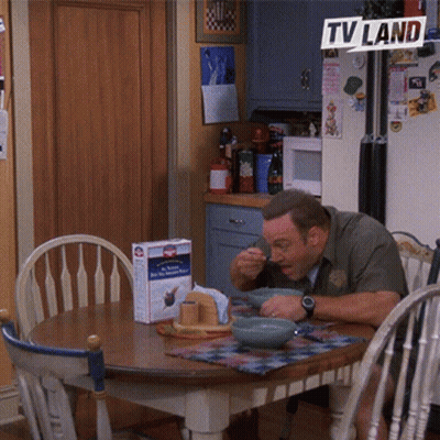 A Man Sits At A Table With Bowls Of Food Under A Tv Land Banner GIF