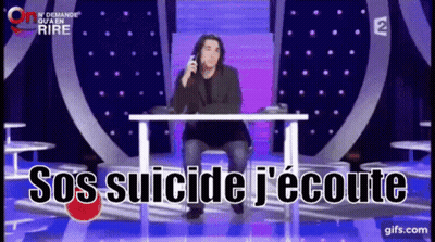 A Man Sits At A Table With The Words Sos Suicide J'écoute Written On The Screen GIF