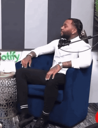 A Man Sits In A Blue Chair In Front Of A Spotify Logo GIF