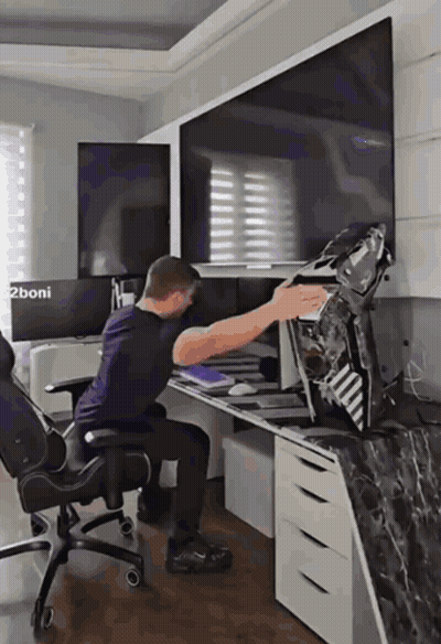 A Man Sits In A Chair In Front Of A Computer Monitor With The Words 2Boni On The Bottom Left GIF