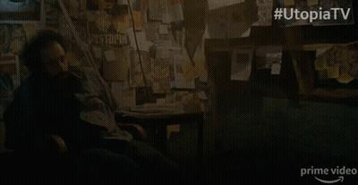 A Man Sits In A Chair In Front Of A Wall With Papers On It And The Words Utopia Tv On The Bottom GIF