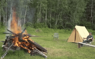 A Man Sits In A Chair Near A Campfire GIF