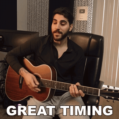 A Man Sits In A Chair Playing An Acoustic Guitar With The Words Great Timing Written Below Him GIF