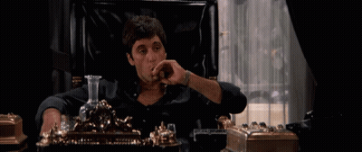 A Man Sits In A Chair Smoking A Cigar And Drinking From A Decanter GIF