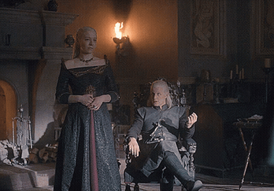 A Man Sits In A Chair While A Woman Stands Behind Him GIF