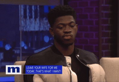 A Man Sits In A Chair With A Sign That Says " Leave Your Wife For Me Today " GIF