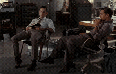 A Man Sits In A Chair With His Feet Up While Another Man Sits In A Chair GIF