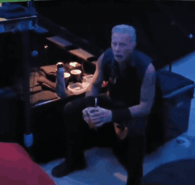 a man sits in a dark room drinking from a cup