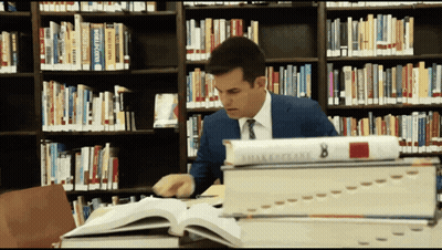 A Man Sits In A Library Surrounded By Books Including One Titled Shakespeare 8 GIF