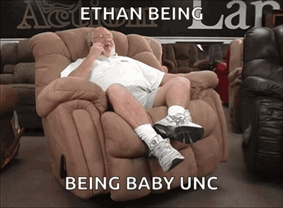 A Man Sits In A Recliner With The Words " Ethan Being Being Baby Unc " Written Below Him GIF