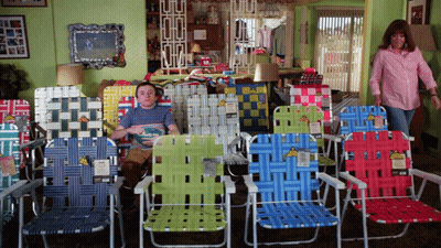 A Man Sits In A Row Of Lawn Chairs With A Yellow Tag That Says ' Lawn Chairs ' GIF