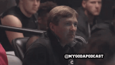 A Man Sits In A Stadium Watching A Game With The Hashtag Mygodapodcast GIF