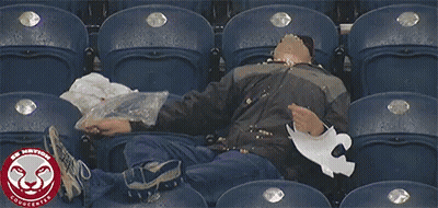 A Man Sits In A Stadium With The Word Cougcenter On The Bottom Left GIF