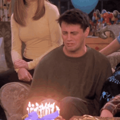 A Man Sits In Front Of A Birthday Cake With Candles GIF