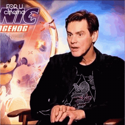 A Man Sits In Front Of A Sonic The Hedgehog Poster GIF