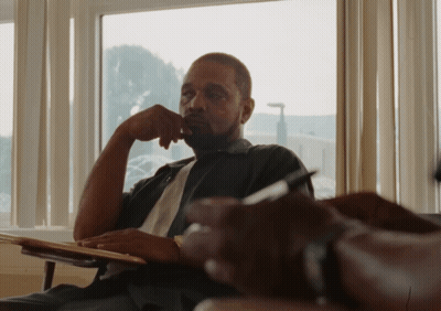 A Man Sits In Front Of A Window With His Hand To His Chin GIF