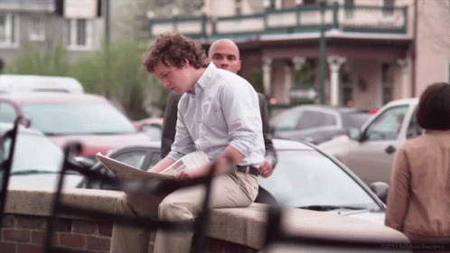 A Man Sits On A Brick Wall Looking At A Piece Of Paper With The Year 2011 On The Bottom Right GIF