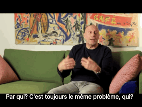 A Man Sits On A Green Couch In Front Of A Cafe Painting GIF