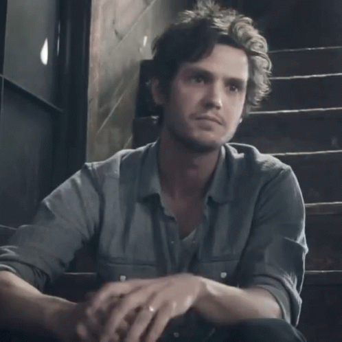 A Man Sits On A Set Of Stairs With The Word Sissy Written On The Front Of His Shirt GIF