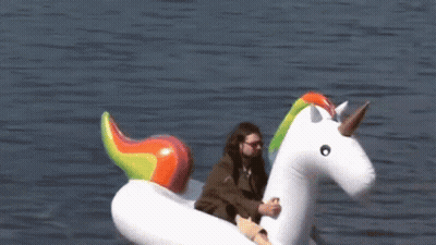 A Man Sits On An Inflatable Unicorn Floating In The Water GIF