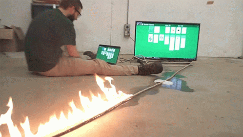 A Man Sits On The Floor Playing A Game Of Solitaire On His Laptop GIF