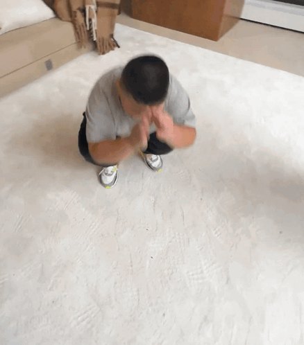 A Man Sits On The Floor With His Hands Folded In Prayer GIF